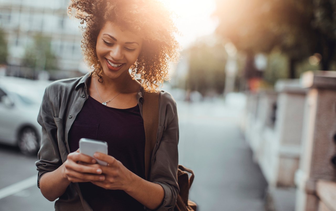 Close up of a young lady using a phone while on the street