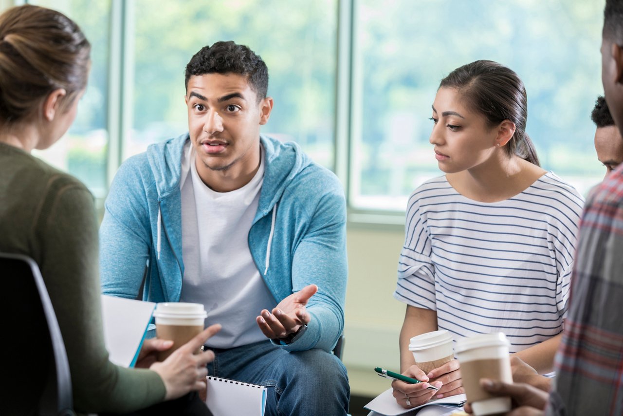 Young African American man gestures as he discusses something in a group therapy session